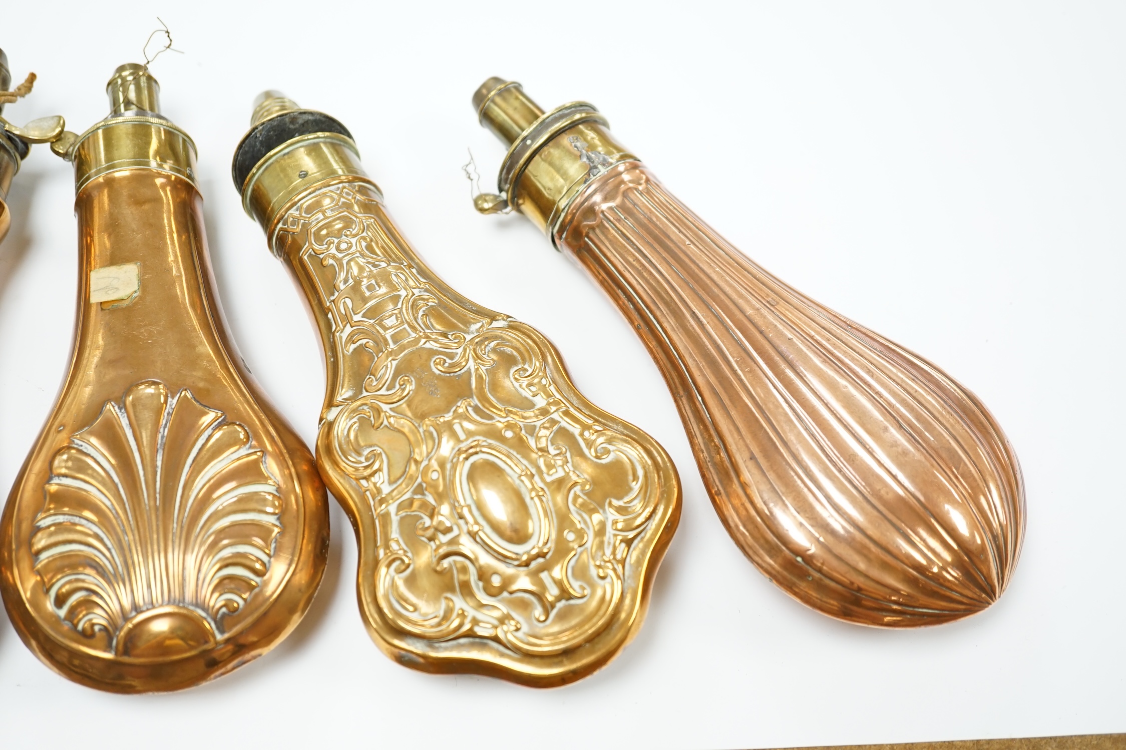 Five 19th century copper and brass powder flasks, all with embossed decoration to the bodies. Condition - fair